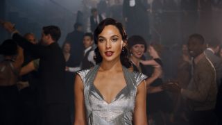 Gal Gadot walking through a dance floor in a silver dress in Death on the Nile.