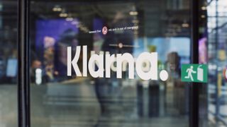 The Klarna logo written in white text on a glass exit door to an office.