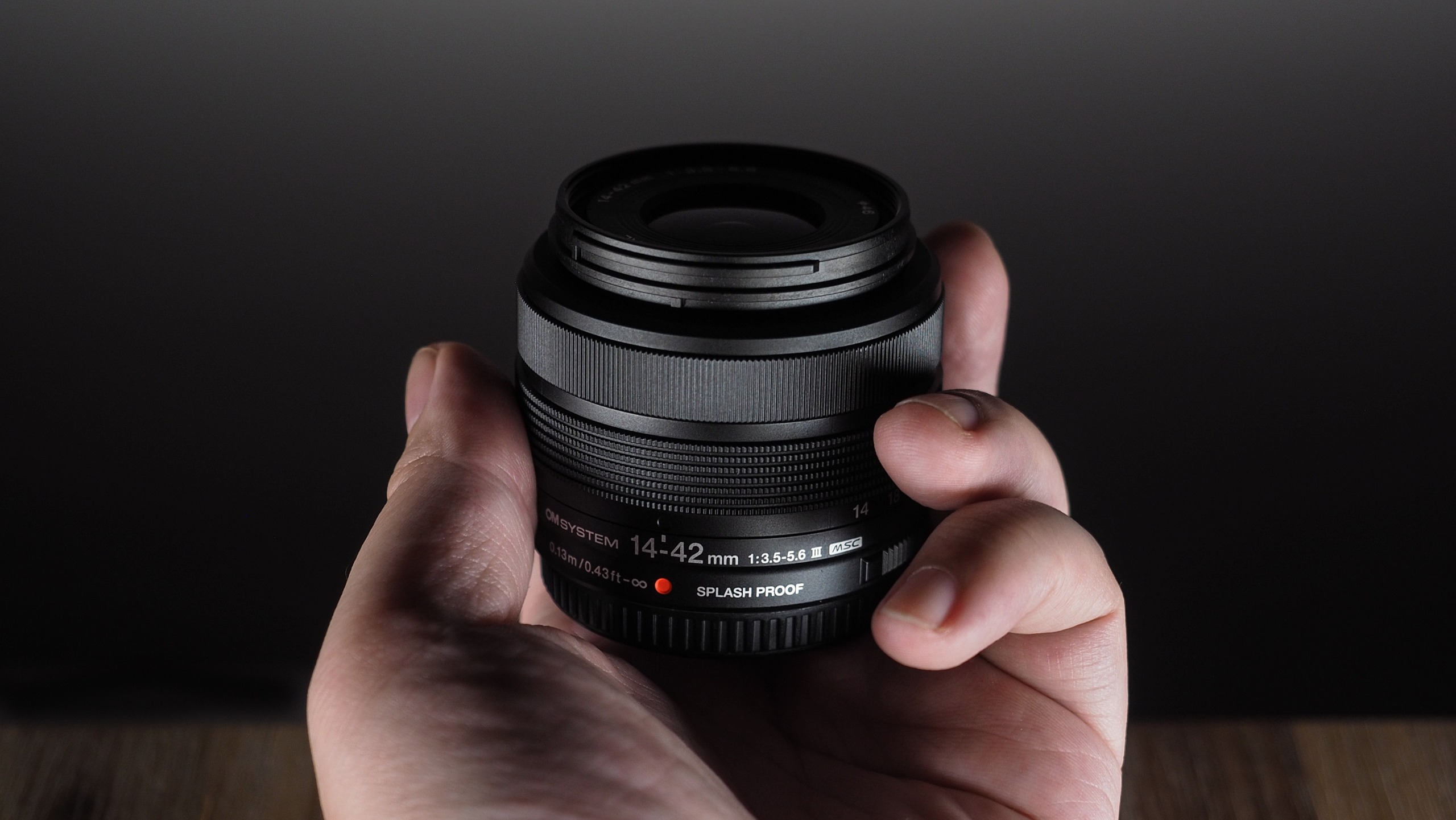 OM System M.Zuiko 14-42mm 3.5-5.6 III being held in hand