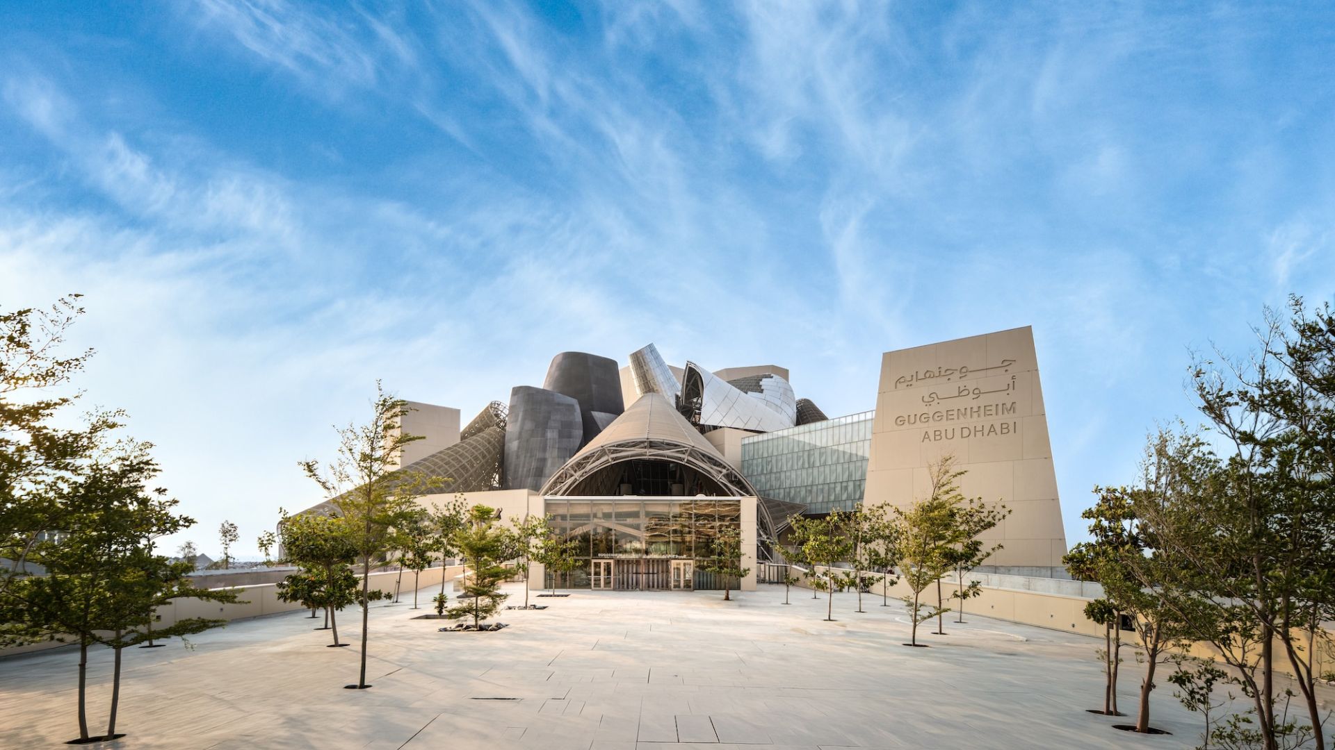 Guggenheim Abu Dhabi exterior images featuring a geometric assemblage of volumes made from steel glass timber and stone