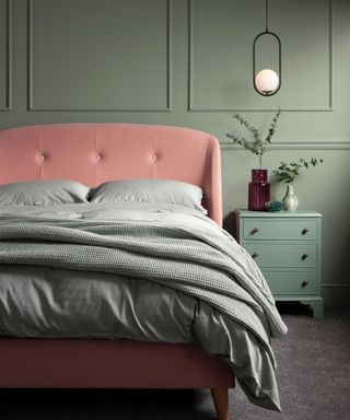 A light green bedroom with a blush pink bedframe and matching green bedding.