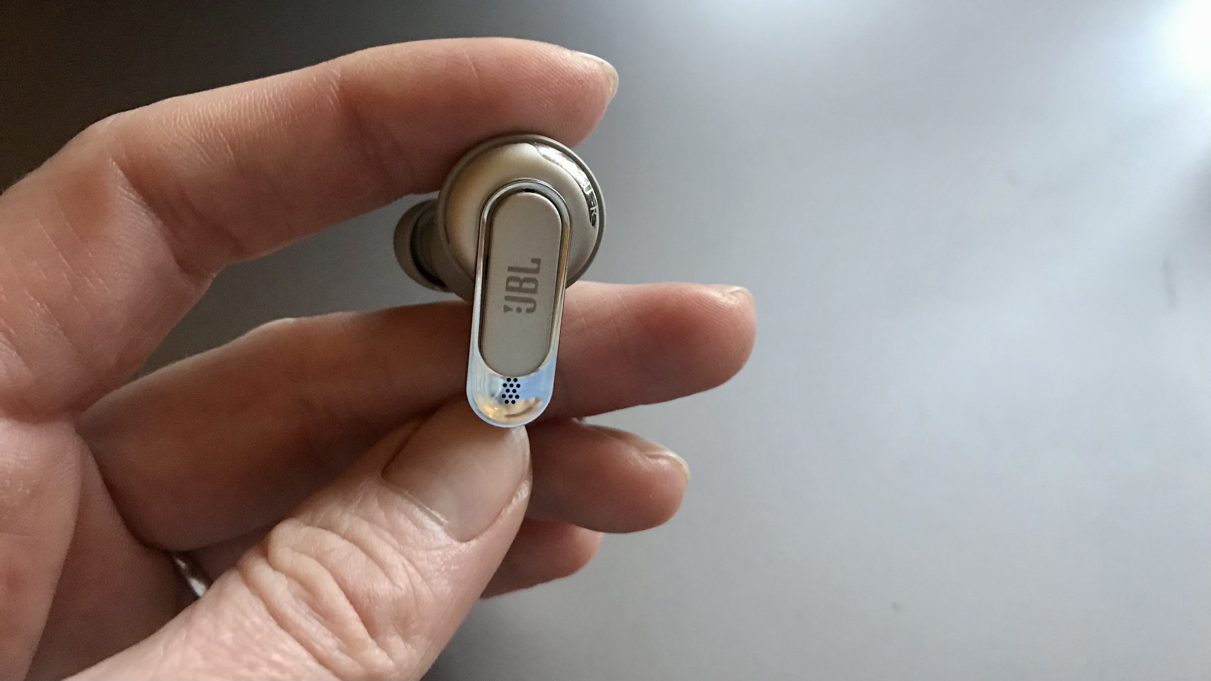 JBL Tour Pro 2 earbud held in a hand