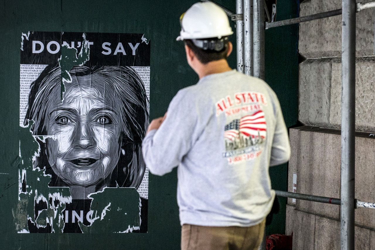 A worker looks at a Hillary Clinton poster in New York.