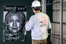 A worker looks at a Hillary Clinton poster in New York.