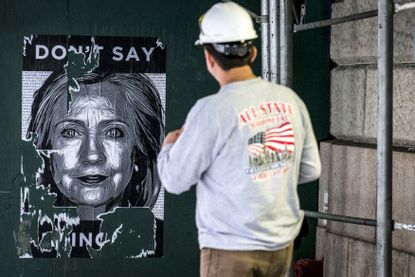 A worker looks at a Hillary Clinton poster in New York.