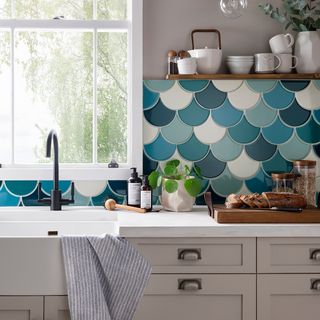 kitchen with fish scale tile wall white cabinet window and wooden shelf