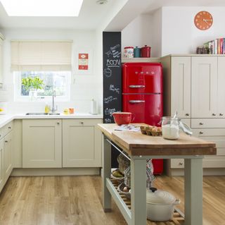 A neutral kitchen with a red fridge freezer and freestanding island