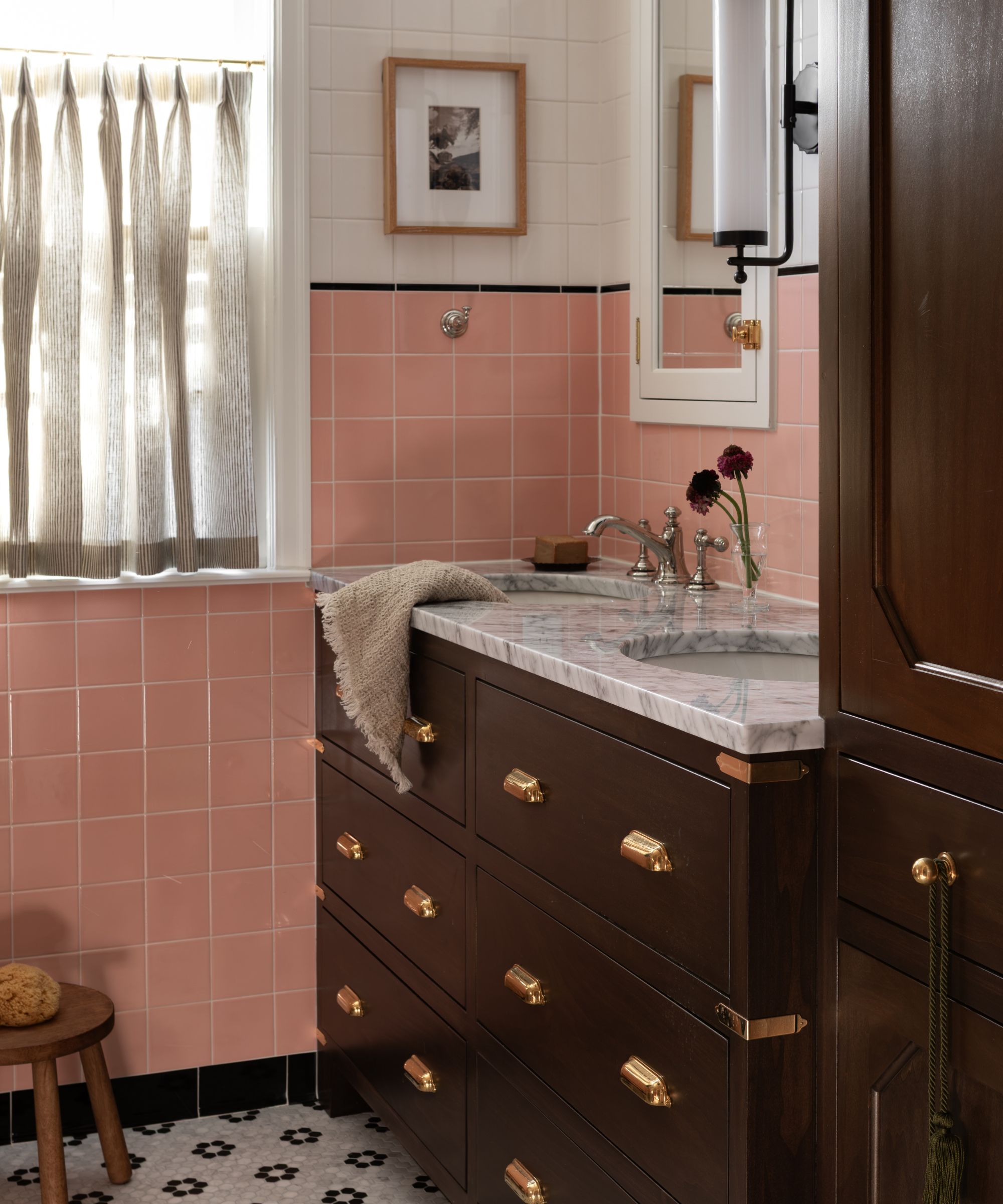vintage 1940s style bathroom with mosaic floor tiles, half pink and white bathroom wall tiles and dark wood cabinetry with a double marble topped vanity
