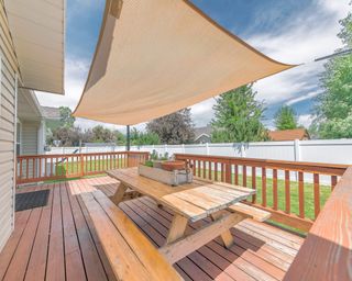 Deck of a house with wooden chairs and table under a shade sail