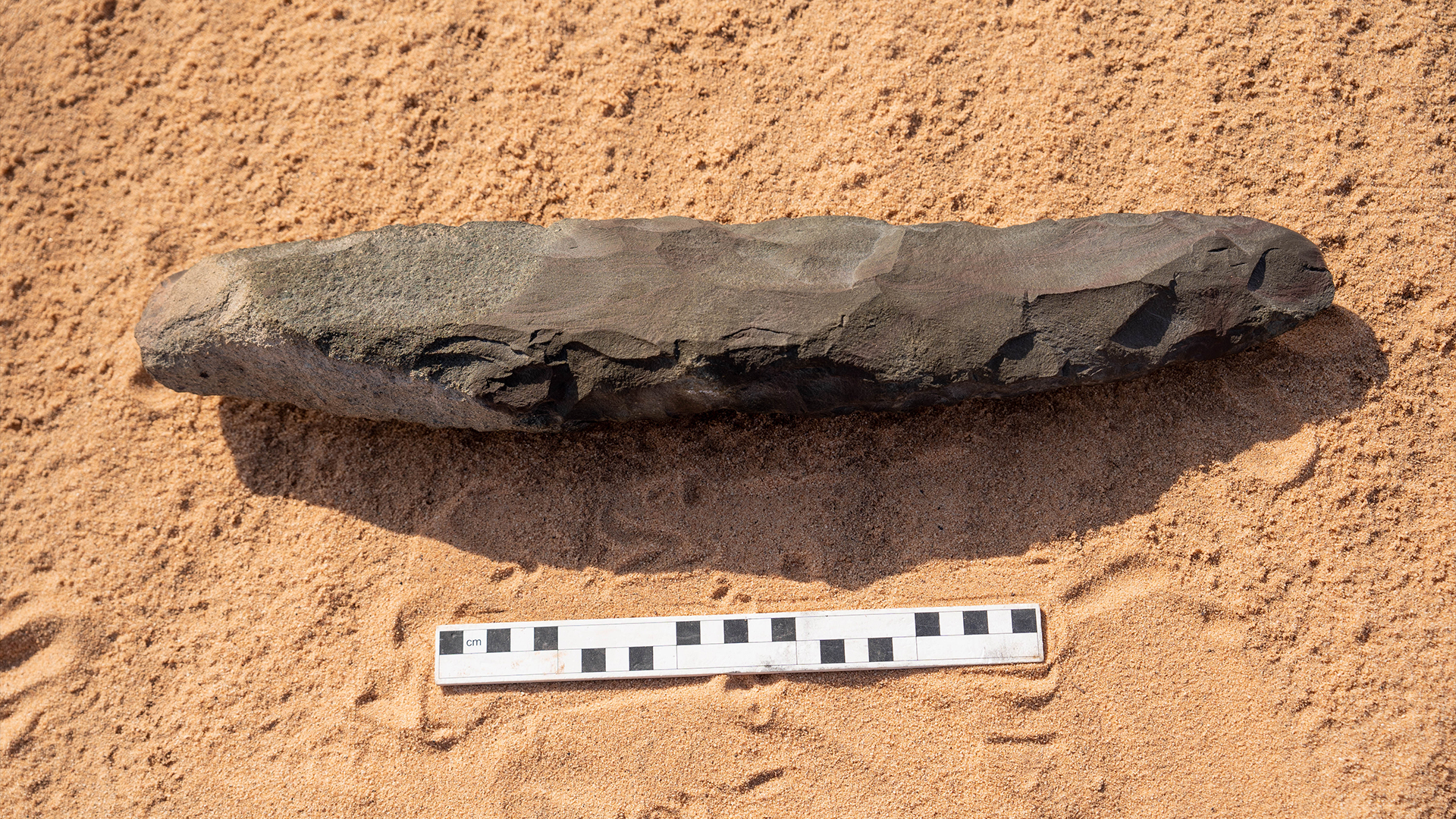 A long stone hand ax on the sand