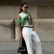 Influencer wears a colourful jumper on top of a white outfit.