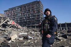 Ukrainian policeman standing among rubble