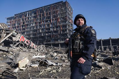 Ukrainian policeman standing among rubble