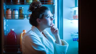 Woman looking in the fridge at night