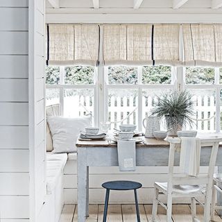 coastal dinning table with chair white walls white window and potted plants