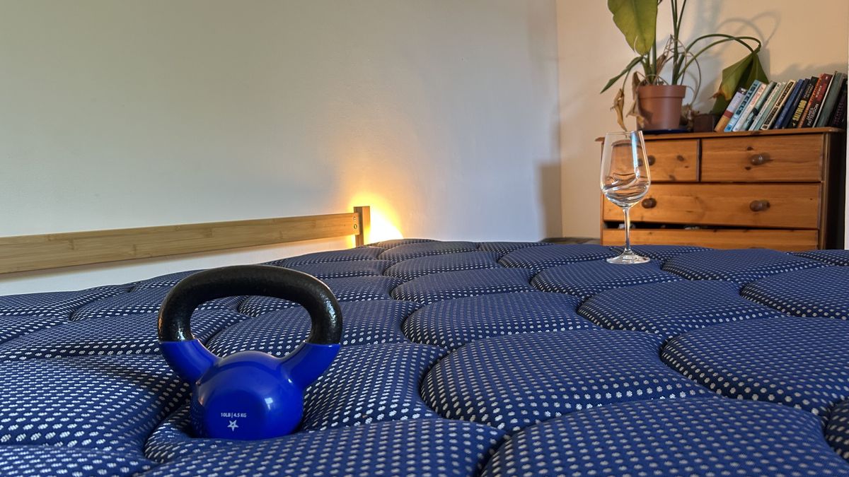 A weight resting on the DreamCloud Luxe Memory Foam mattress next to a wine glass to measure motion isolation