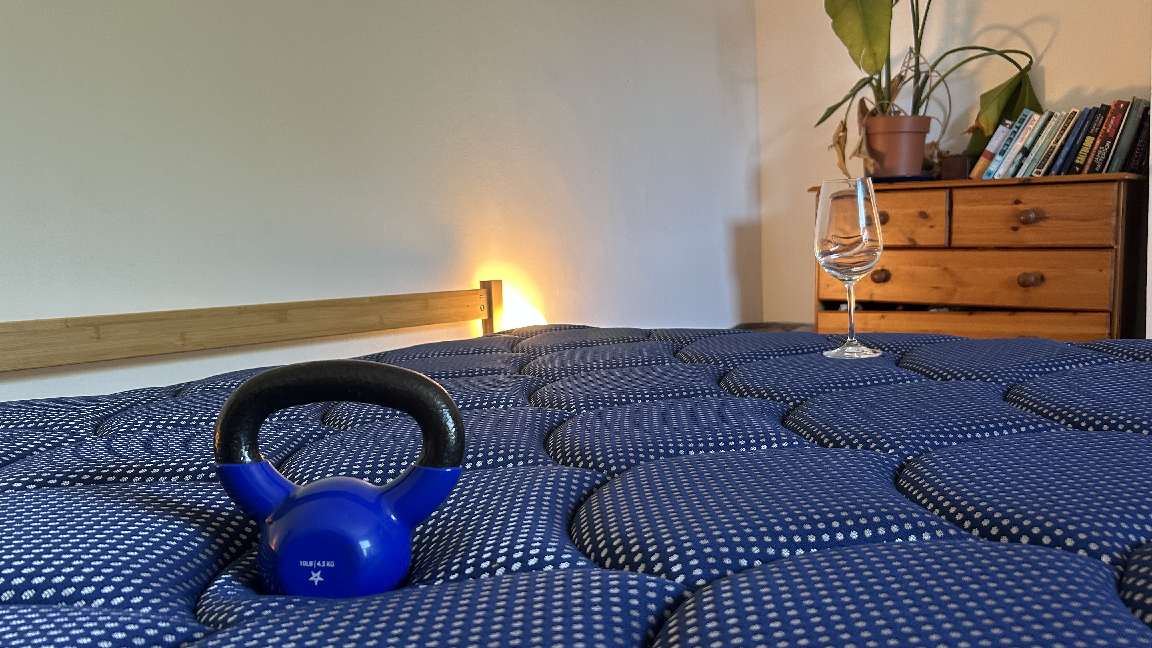 A weight resting on the DreamCloud Luxe Memory Foam mattress next to a wine glass to measure motion isolation