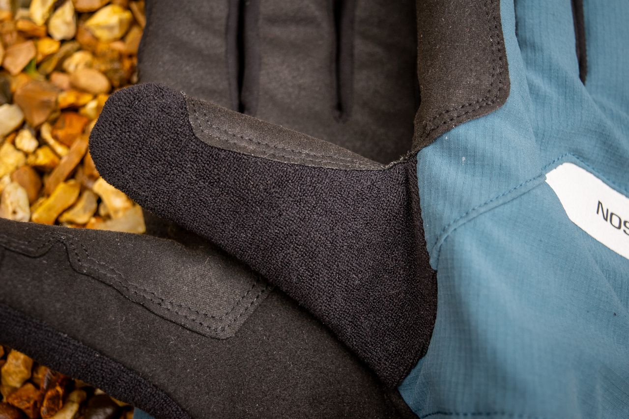 A pair of blue Madison DTE waterproof gloves on gravel