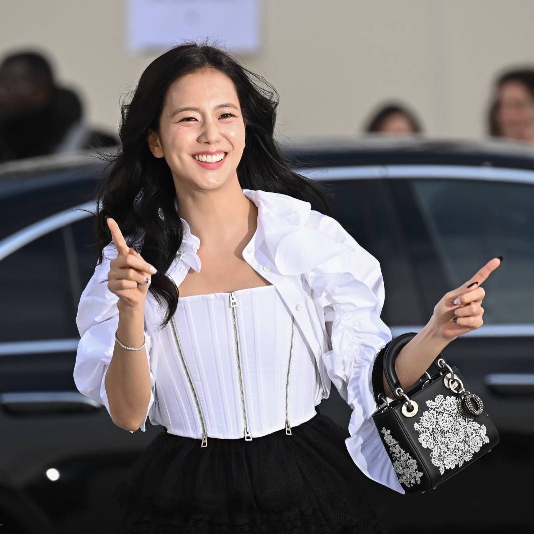 Jisoo smiling and pointing outside a car