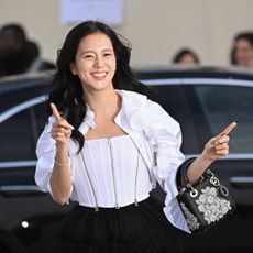 Jisoo smiling and pointing outside a car