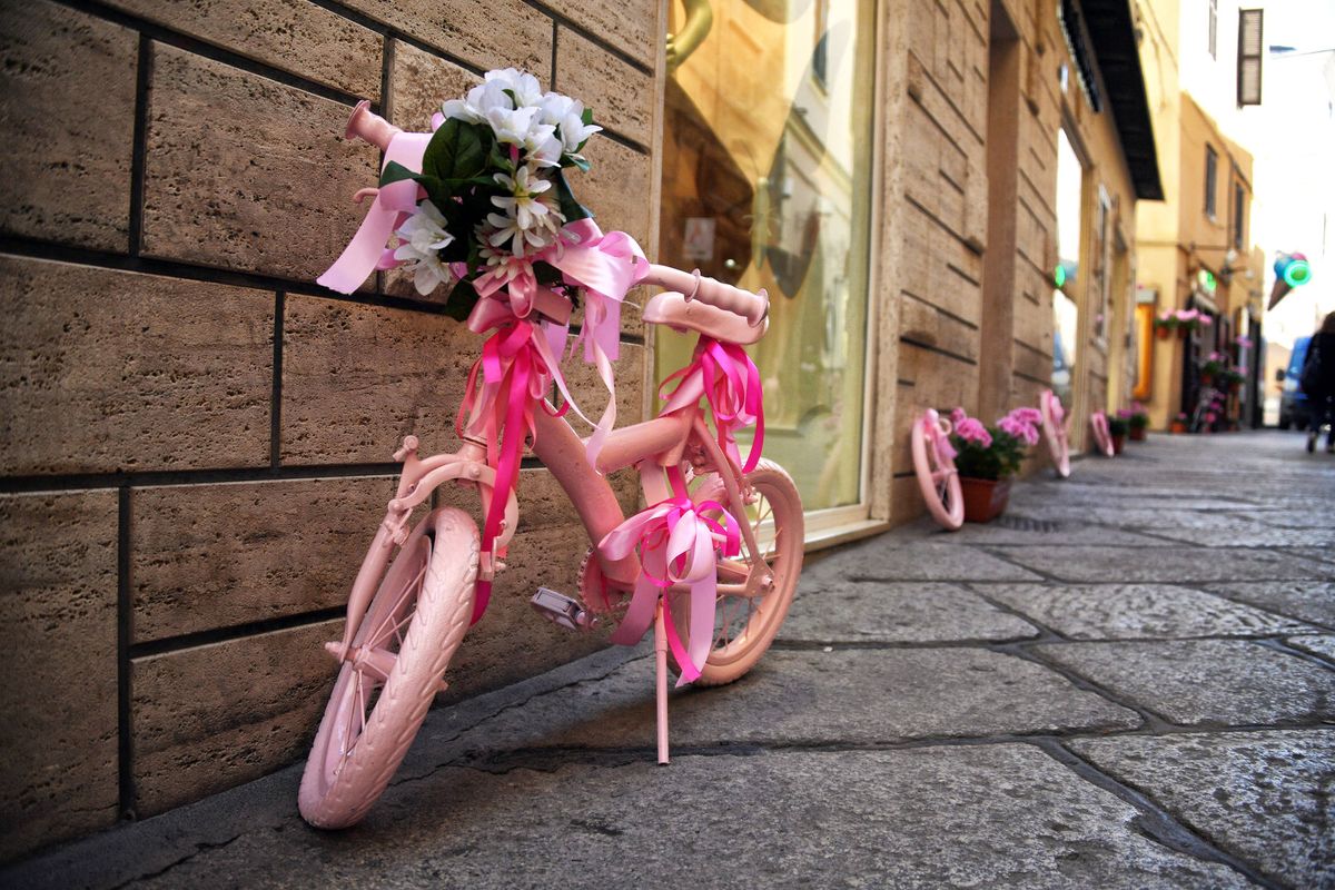 A painted child's bike sits outside a shop front