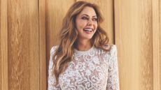 Carol Vorderman in a white lace playsuit smiling and looking off camera