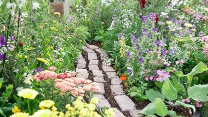 reclaimed brick path leading through the middle of pretty flowerbeds