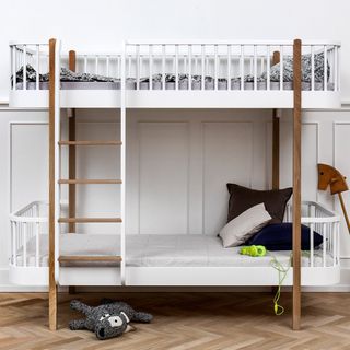 Super-stylish designer bunk bed on wooden floor with toys and bedding on it