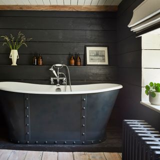 luxury style bathroom with black cast iron bath and wood panelled walls