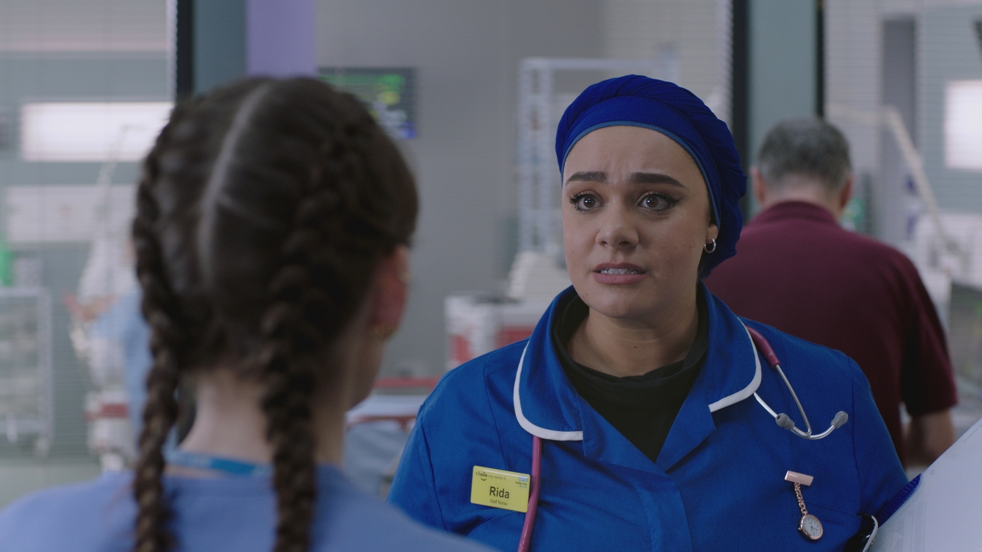 Rida in her new dark blue uniform and headscarf talks seriously to Jodie.