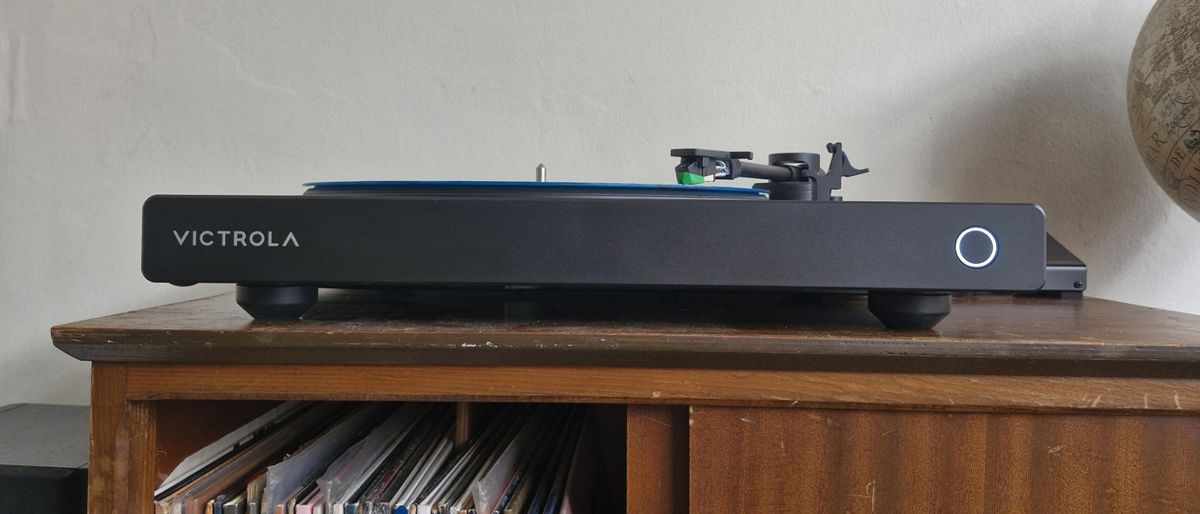 The Victrola Hi-Res Onyx turntable on a wooden sideboard with records underneath and a globe next to it.