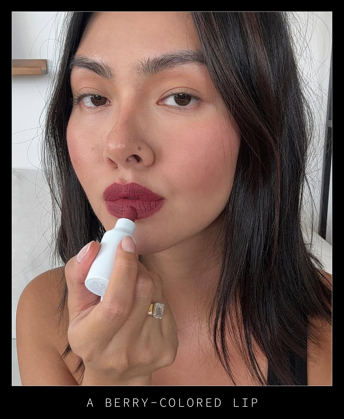Woman putting on berry lipstick.