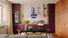 Kitchen with aubergine painted cabinets, marble countertops, parquet flooring, wood cabinets and dining table