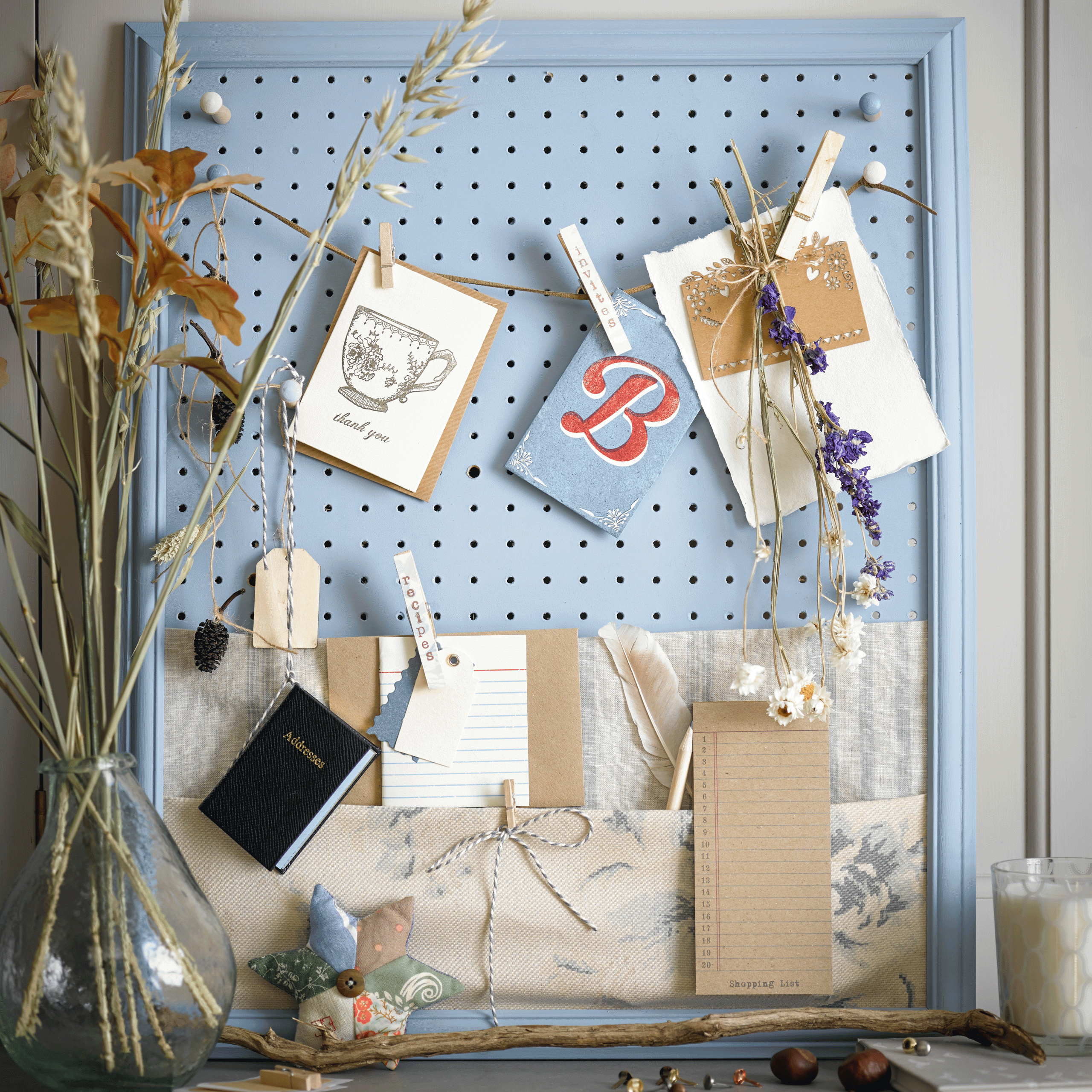 A blue peg board with assorted art and crafting materials attached to it.