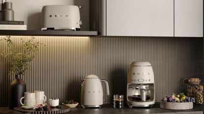 A set of matte cream colored SMEG appliances on a black kitchen counter