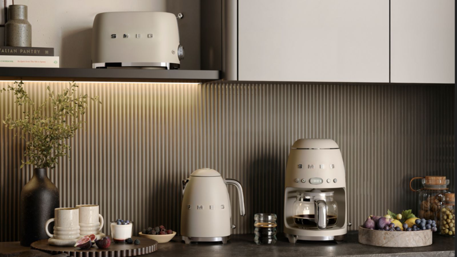 A set of matte cream colored SMEG appliances on a black kitchen counter