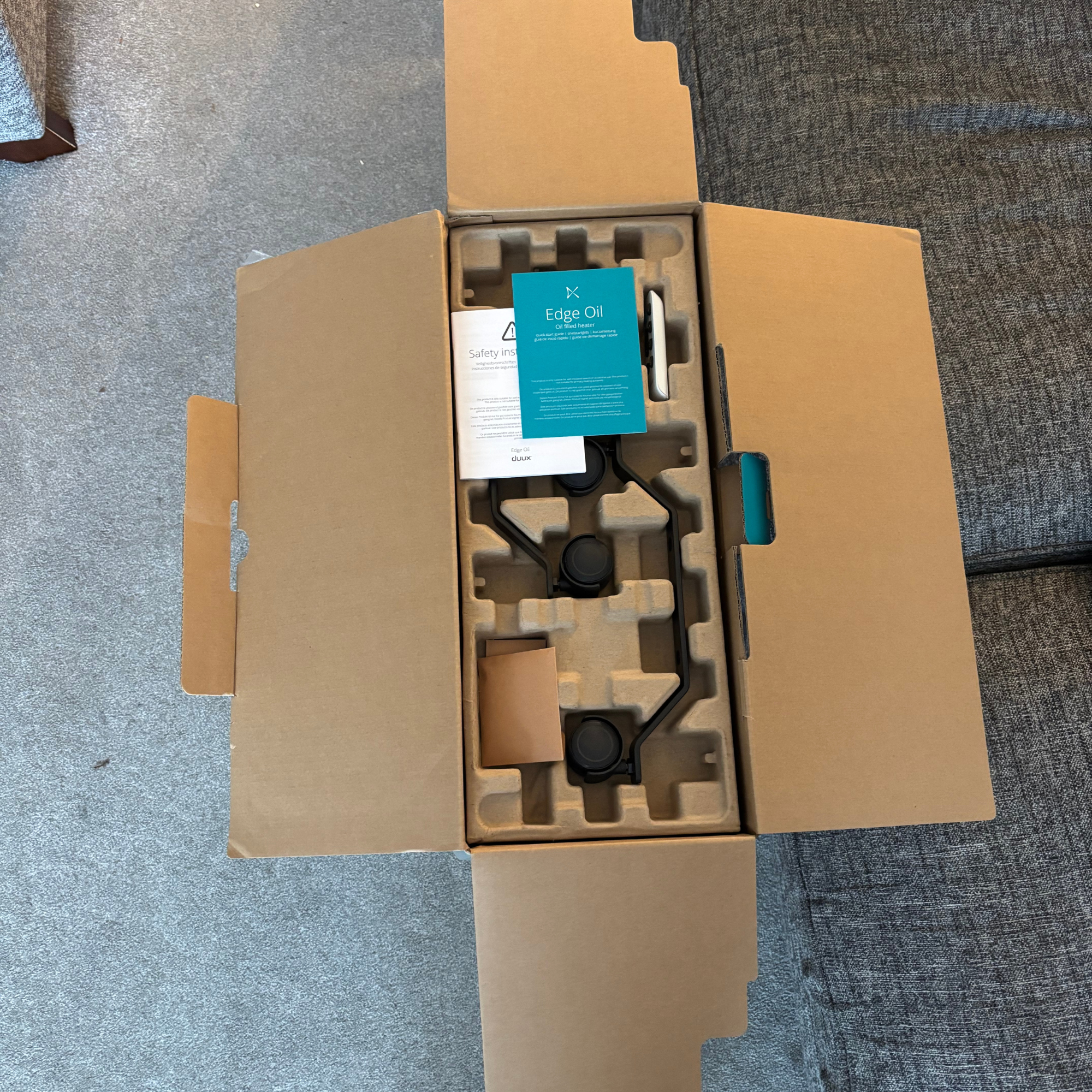Rectangular cardboard box opened with Duux Edge Oil 2000W Oil-Filled Radiator securely placed beneath moulded cardboard
