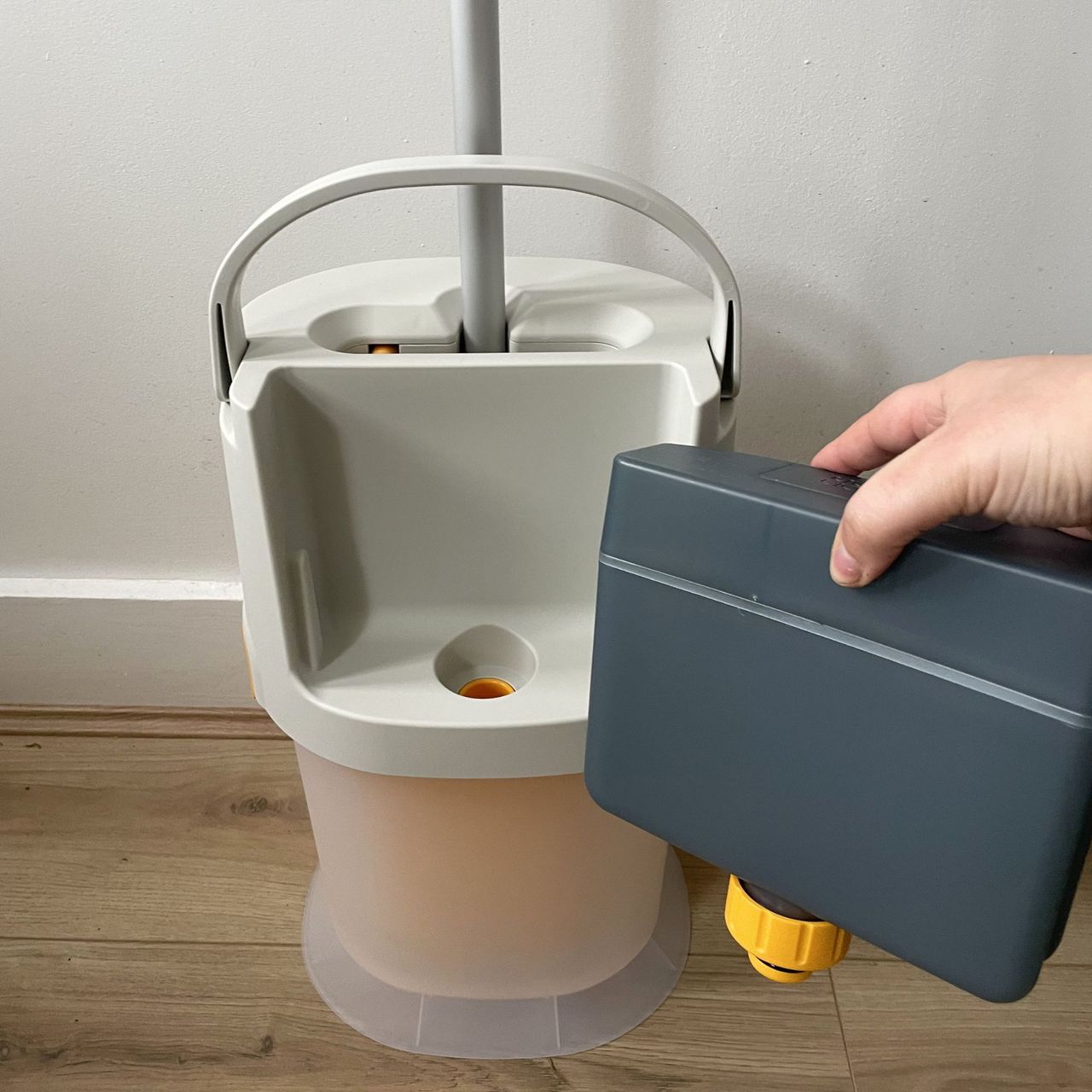 Hand holding the clean water tank in front of the Joseph Joseph UltraClean mop