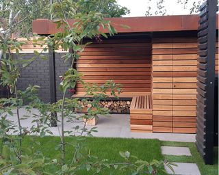 timber clad shed and covered seating area with log storage