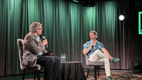 Chris Dring interviews Xbox Chief Strategy Officer Matthew Ball on stage during a live event, with both seated in armchairs holding microphones under green lighting.