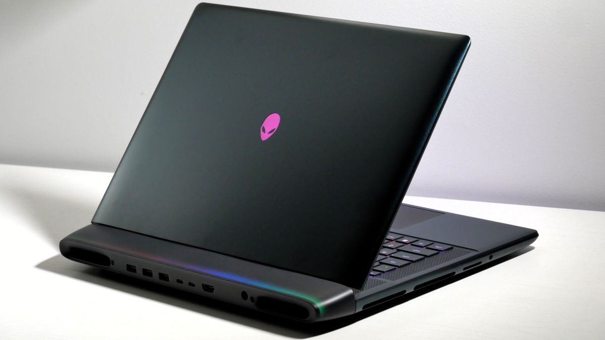 Alienware 16 Area-51 (RTX 5080) open at an angle on a white desk, highlighting the keyboard, lid, and light bar on the hinge.