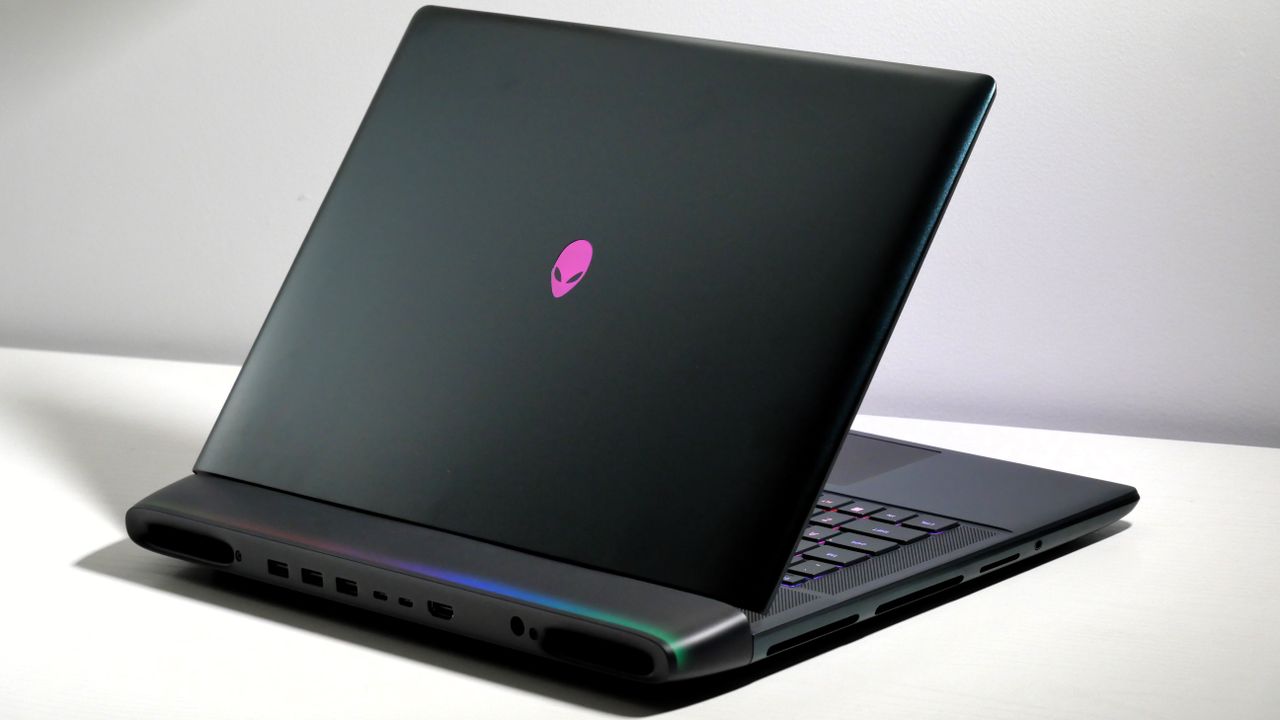 Alienware 16 Area-51 (RTX 5080) open at an angle on a white desk, highlighting the keyboard, lid, and light bar on the hinge.