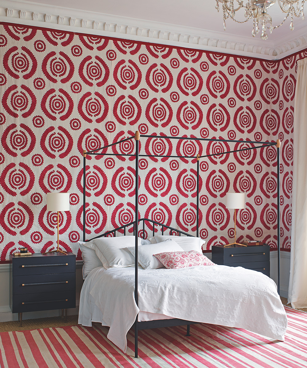 Bedroom wallpaper ideas shown in a bright red and white pattern, with red and white striped rug and a four poster bed.