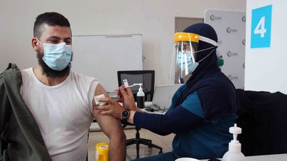 Registered Nurse Ririn Widiashi administers a Pfizer vaccine to a client at the Lebanese Muslim Association in Lakemba on Aug. 8, 2021, in Sydney, Australia.