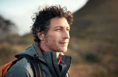 Portrait of an older, fit man hiking, looking away from the camera.