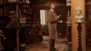 Gabriel (Jon Hamm) in his assistant bookseller get-up looking at books in Good Omens season 2 episode 2