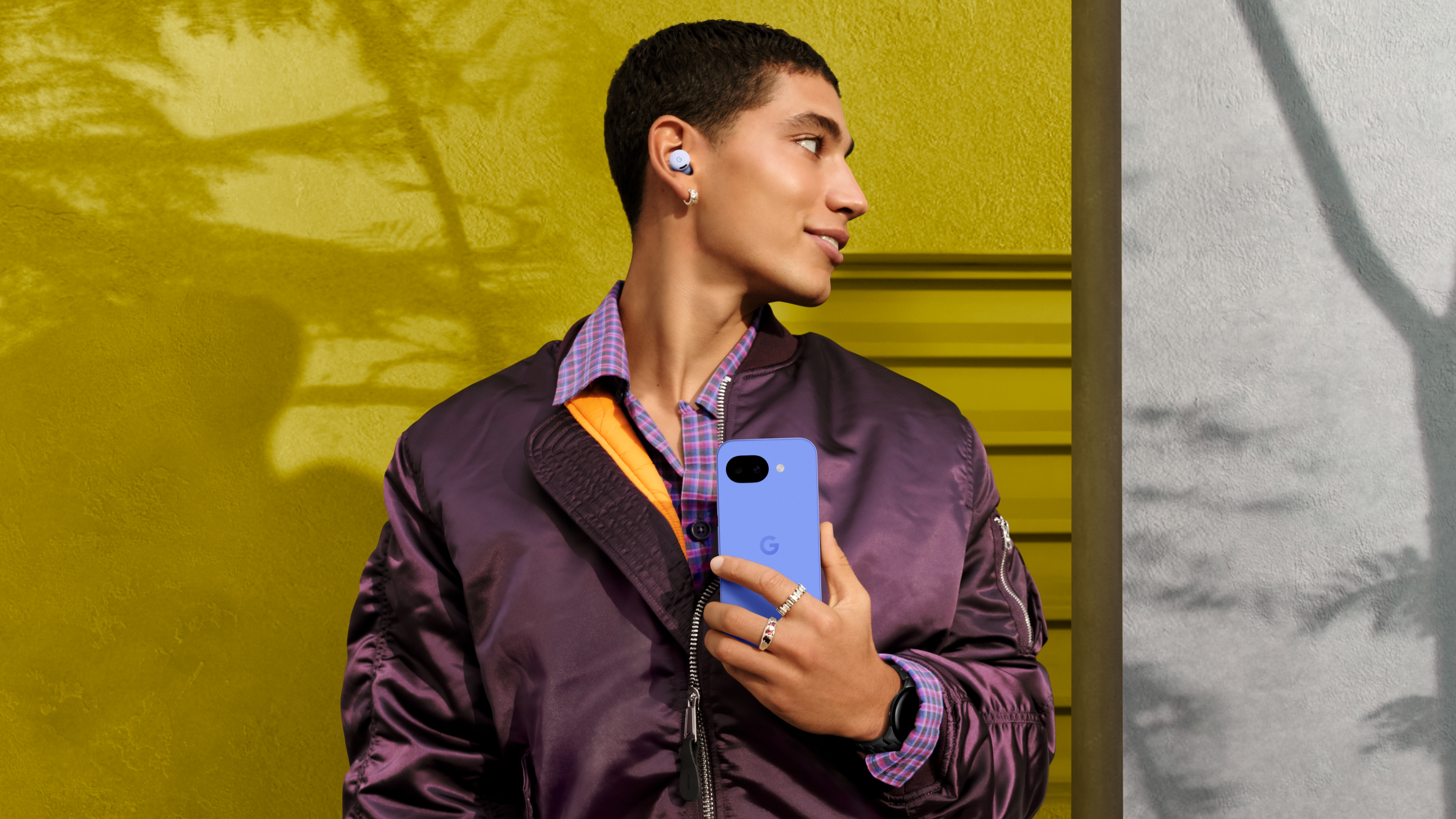 A man holding the Google Pixel 10a and wearing the Pixel Buds 2a.