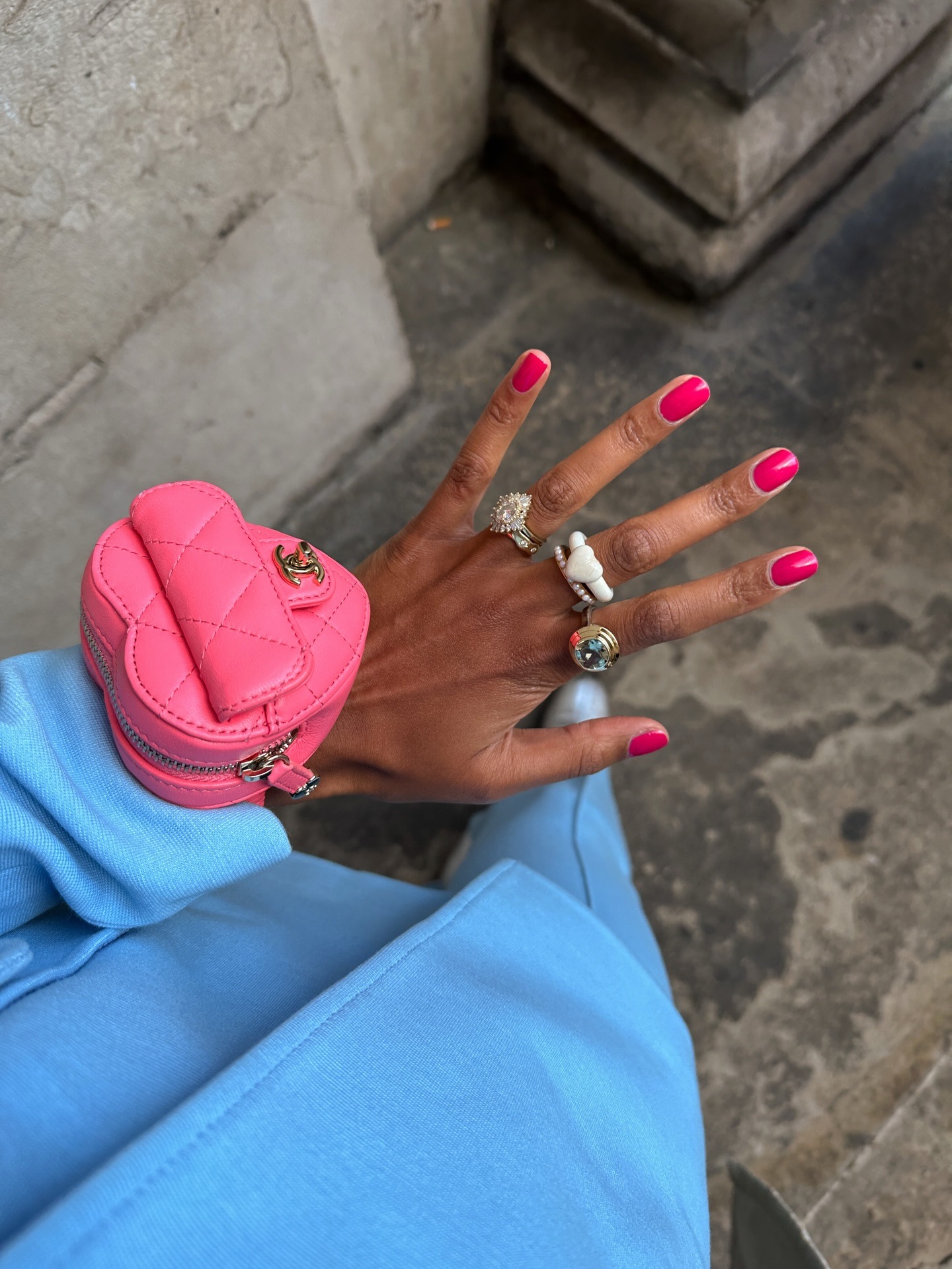 A woman wearing a pink Chanel heart wrist bag with a hot pink manicure