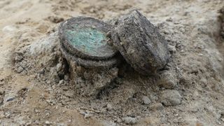 A small pile of greenish coins in the dirt