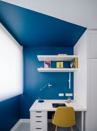 A bedroom with a home office within an alcove